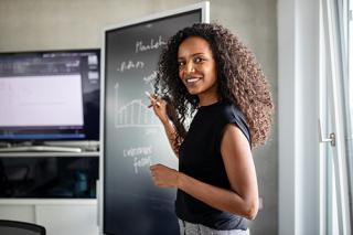 Women teaching and writing on a chalk board